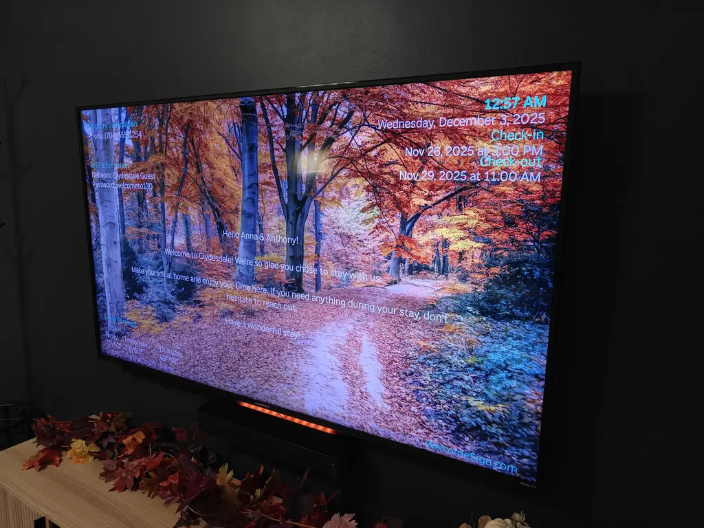 Vacation rental TV welcome screen displaying WiFi password, weather forecast, and check-in times